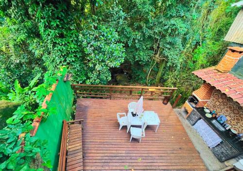 a wooden deck with two chairs and a table at Casa DaJu - 6 minutos do cais da Vila do Abraão em Ilha Grande - Angra dos Reis in Angra dos Reis