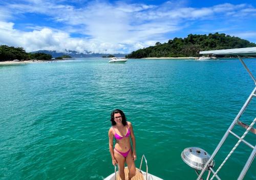 a woman in a bikini standing on a boat in the water at Casa DaJu - 6 minutos do cais da Vila do Abraão em Ilha Grande - Angra dos Reis in Angra dos Reis