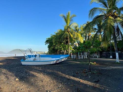 un barco sentado en una playa con palmeras en Cabaña Viento - RiverBeach, en Jacó