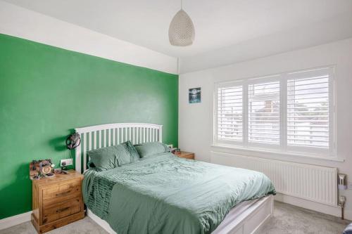 Dormitorio verde con cama y ventana en A Spacious 2 Bed Home in a Central Location, en Bishops Stortford
