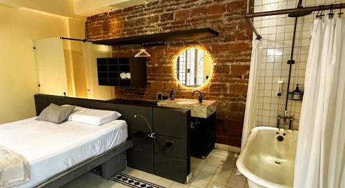 Casa Charlotte - Alma Hotels في سانتا مارتا: حمام به سرير وحوض استحمام ومغسلة