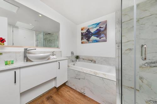 a white bathroom with a sink and a shower at The Charming Cracker! in Auckland