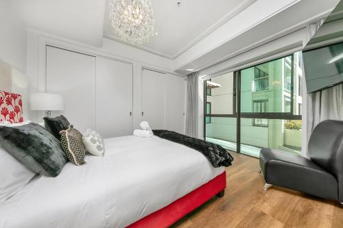 a bedroom with a large bed and a chair at The Charming Cracker! in Auckland
