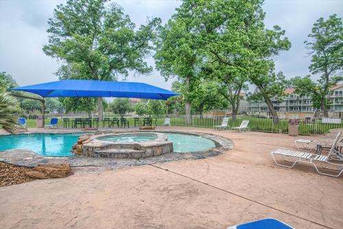 una piscina con sombrilla y sillas azules en Remington River Retreat WW C201, en New Braunfels