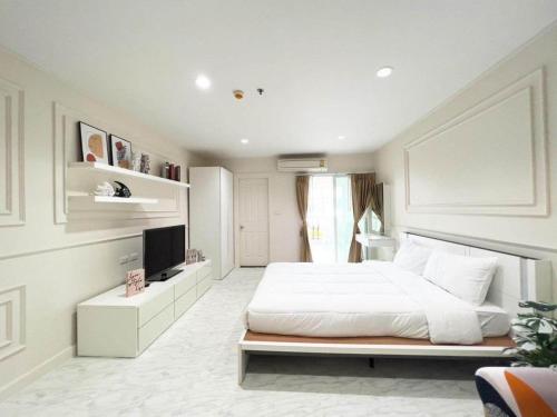 a white bedroom with a bed and a television at Vacation pool condo in Ban Rangeng