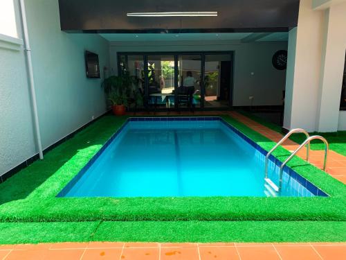 a swimming pool with artificial grass in a house at Five Homes Hotel and Apartments in Abuja