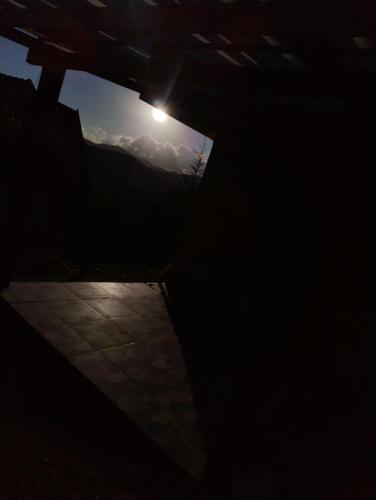 a dark room with the sun shining through a window at Casas boa vista in Campos do Jordão