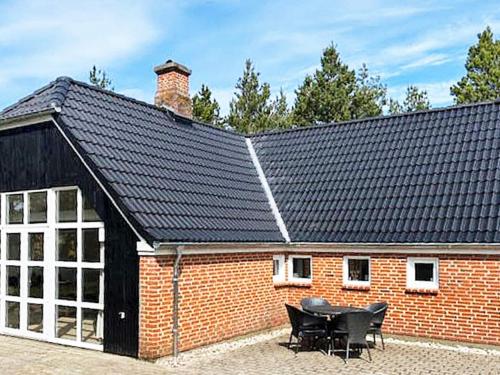 un edificio con techo negro y mesa en 10 person holiday home in N rre Nebel, en Lønne Hede