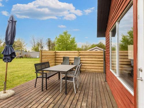 einen Tisch und Stühle auf einer Terrasse mit einem Sonnenschirm in der Unterkunft 6 person holiday home in Nibe in Nibe