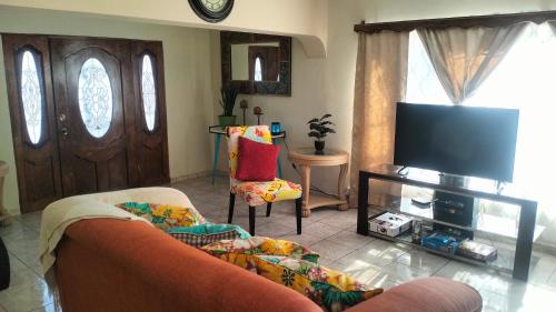 ein Wohnzimmer mit einem Sofa und einem Flachbild-TV in der Unterkunft Geranios in Ciudad Juárez