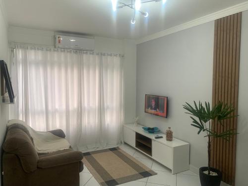 sala de estar blanca con silla y ventana en Apartamento em Santos no Gonzaga em frente a praia en Santos