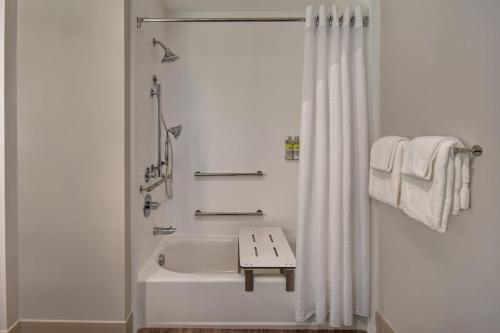 a white bathroom with a bath tub and a shower curtain at Holiday Inn Express & Suites - Galveston Beach by IHG in Galveston