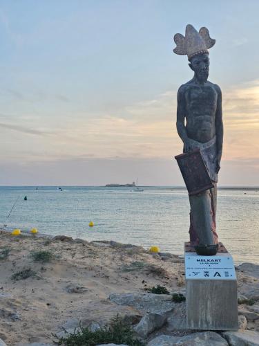 Una statua di un uomo in piedi sulla spiaggia di Apartamento vacacional máximo 4 personas a Novo Sancti Petri