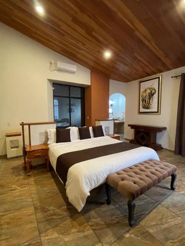 una grande camera da letto con un grande letto e una panca di Hotel & Balneario Los Angeles a Taxco de Alarcón
