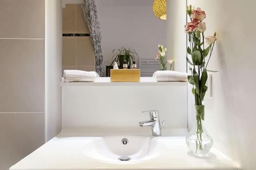 La salle de bains est pourvue d'un lavabo et d'un vase de fleurs. dans l'établissement Appartement spacieux avec loggia proche métro, à Saint-Ouen