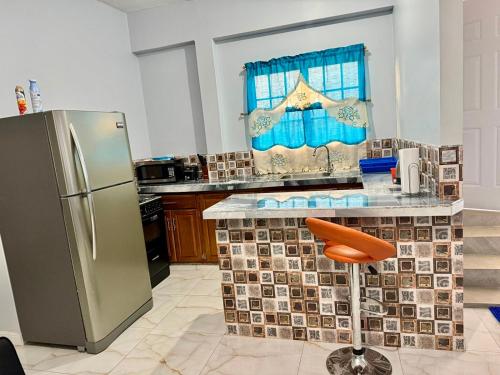 a kitchen with a stainless steel refrigerator and a counter at Piarco Airport Guest House in Piarco