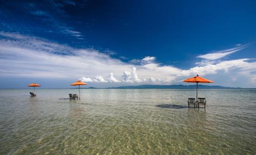 two chairs and umbrellas in the water on a beach at Chantaramas Beach Resort Koh Phangan in Baan Khai