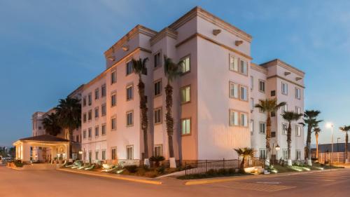 薩爾蒂約的住宿－voco Saltillo Suites, an IHG Hotel，一座白色的大建筑,前面有棕榈树