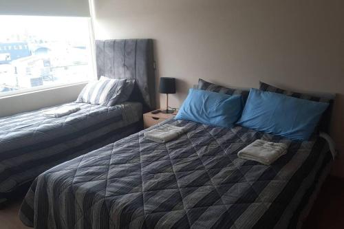 une chambre avec un grand lit et une fenêtre dans l'établissement Departamento Centro Chillán con estacionamiento, à Chillán