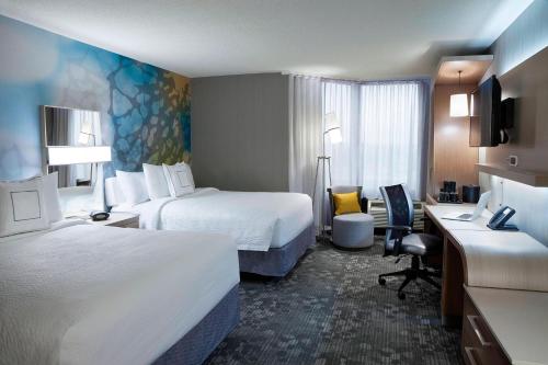 マーカムにあるコートヤード バイ マリオット トロント ノースイースト マークハムのベッド2台とデスクが備わるホテルルームです。