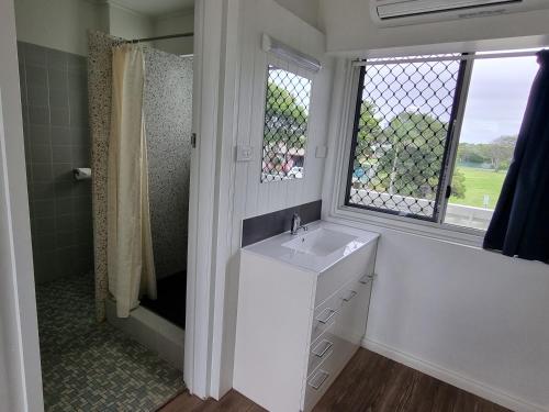 a white bathroom with a sink and a shower at Bargara Beach Hotel in Bargara
