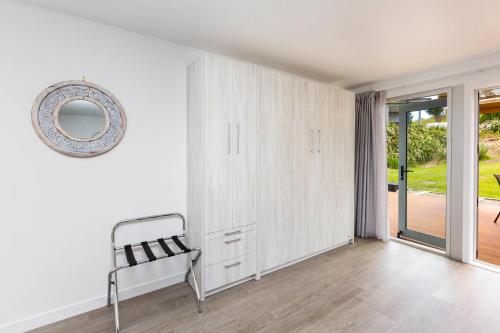 a white room with a chair and a mirror at Waikawa Beach Pod in Manakau