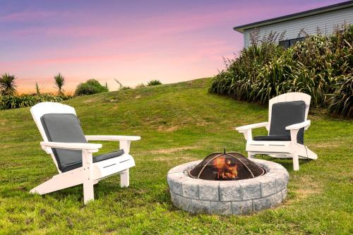 two chairs and a fire pit in a yard at Waikawa Beach Pod in Manakau