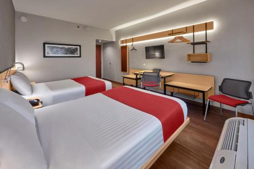 a hotel room with two beds and a desk at City Express by Marriott Chihuahua in Chihuahua