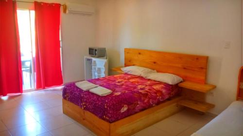 a bedroom with a wooden bed and a red curtain at El Currican Juan Dolio in Juan Dolio