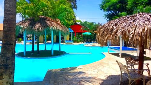a swimming pool with blue water and palm trees at El Currican Juan Dolio in Juan Dolio