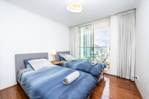 two beds in a room with a large window at CBD Sydney - KING Suite Sussex St 2 Room 1 Parking in Sydney
