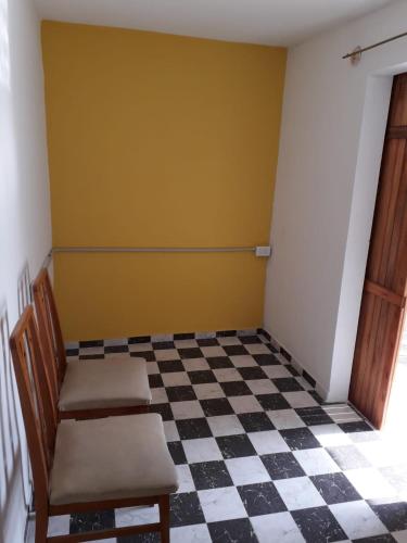 um quarto com duas cadeiras e um piso xadrez em Kasik sacat em Sebastián Elcano