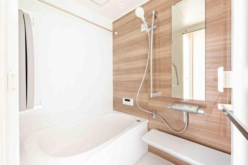 y baño con bañera blanca y espejo. en 渋谷3分でベット4台の3ベットルーム65平米の一軒家, en Tokio