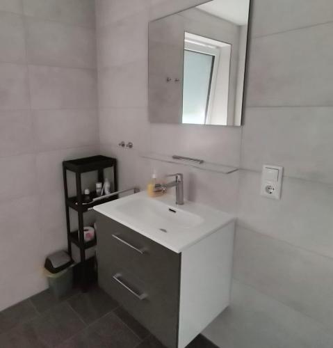 a white bathroom with a sink and a mirror at Ferienwohnung Windkunst in Norden