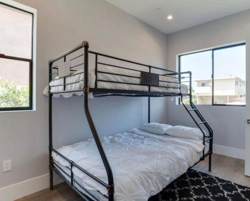 sypialnia z 2 łóżkami piętrowymi i 2 oknami w obiekcie Las Palmas Coliving w Los Angeles