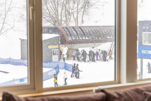 a window with a view of people in the snow at Chalet Murasaki in Kutchan