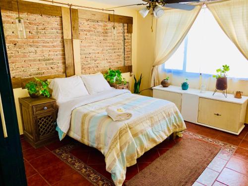 a bedroom with a large bed and a brick wall at Casa Bonita in Guadalajara