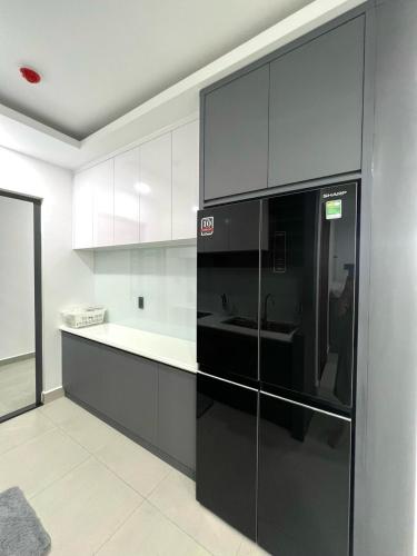 een keuken met een zwarte koelkast en witte kasten bij Căn hộ 2 phòng ngủ tầng 10 chung cư cao cấp Sophia Center in Ấp Rạch Mẹo