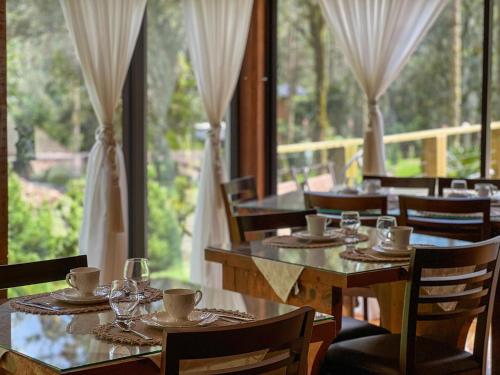 ウルビシにあるPousada Encanto do Avencalのテーブルと椅子、大きな窓のあるレストラン