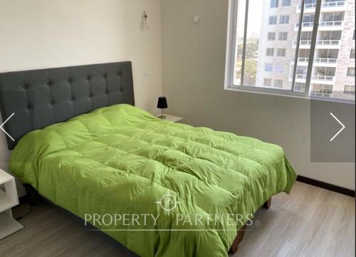1 cama con edredón verde en un dormitorio en Departamento Amoblado en La Serena, en La Serena
