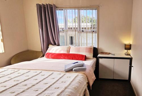 um pequeno quarto com uma cama e uma janela em Miami Stay em Auckland
