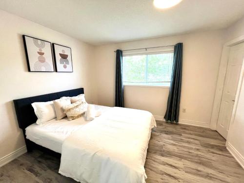 a bedroom with a bed with white sheets and a window at Cozy house near HWY401 & Go station in Scarborough in Toronto