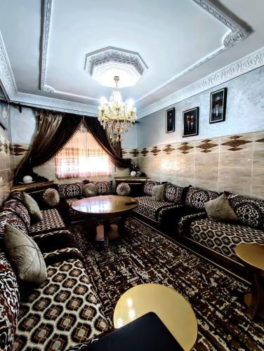 een woonkamer met banken en een kroonluchter bij Appartement luxe et confortable à côté de aswak in Oujda