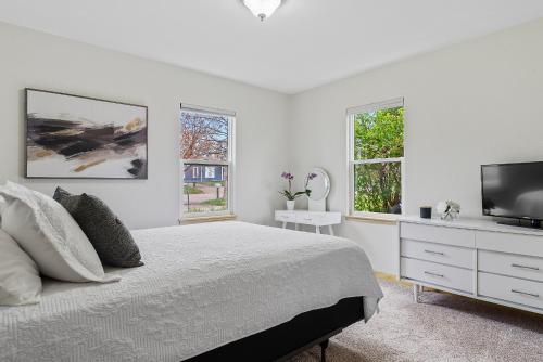 a white bedroom with a bed and a flat screen tv at Covered Patio With Grill Affordable Comfy Stay in Rapid City