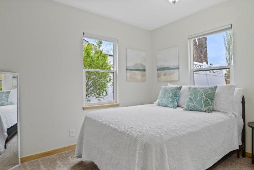 a white bedroom with a bed and two windows at Covered Patio With Grill Affordable Comfy Stay in Rapid City