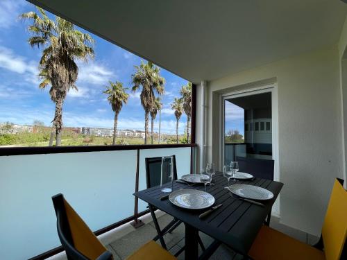 - une salle à manger avec une table, des chaises et des palmiers dans l'établissement Appartement climatisé 3 pièces avec garage à 300m de la plage et des commerces à Sète - FR-1-338-576, à Sète