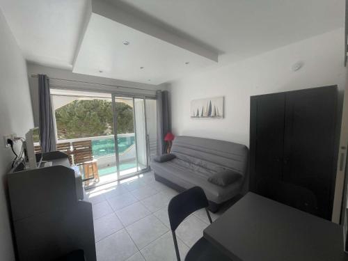 un salon avec un canapé et une grande fenêtre dans l'établissement Studio cosy avec loggia, proche plage - LA FAVIERE, Bormes - FR-1-308-196, à Bormes-les-Mimosas