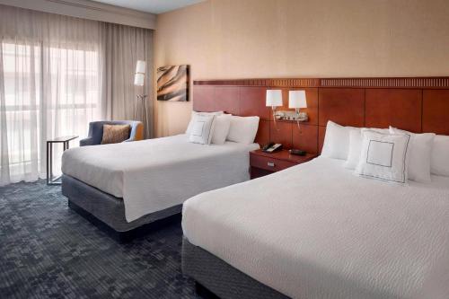 a hotel room with two beds and a chair at Courtyard By Marriott Hartford Windsor Airport in Windsor