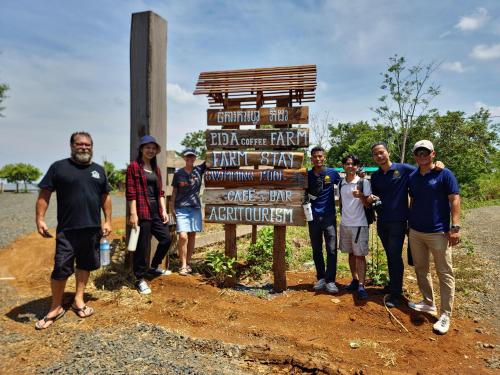 a group of people standing in front of a sign at PIDA COFFEE FARM LODGE in Phumĭ Pu Pal