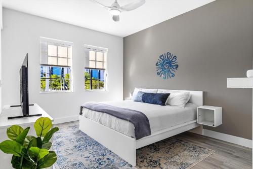 a white bedroom with a bed and windows at Chic & Cozy River District Townhouse in Fort Myers
